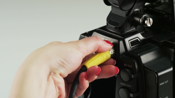 Woman Re-plugging a Yellow Cable To a Video Camera