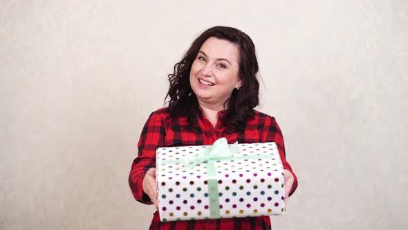 A Woman in a Red Dress Holds a Packed Gift Holds It Out and Then Takes It Back