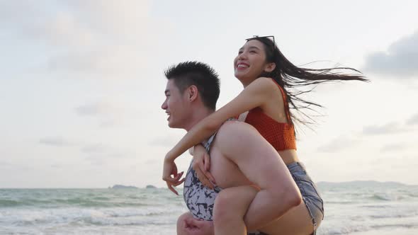 Asian young man and woman having fun, playing on the beach together.