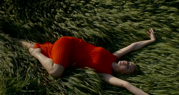 Lady in Dress Lies Relaxed on Wide Green Wheat Field