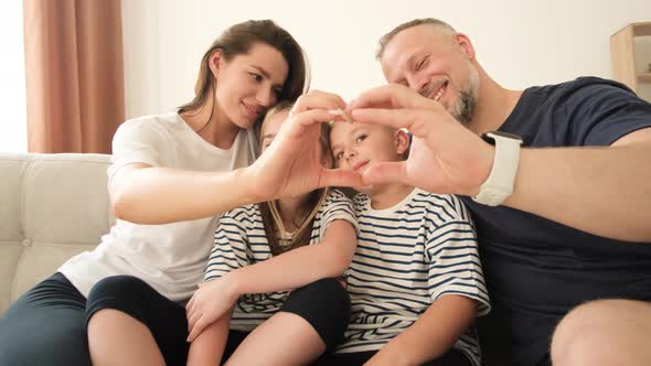 Happy Family with Children Looking Through Connected Fingers Creating a Heart Shape