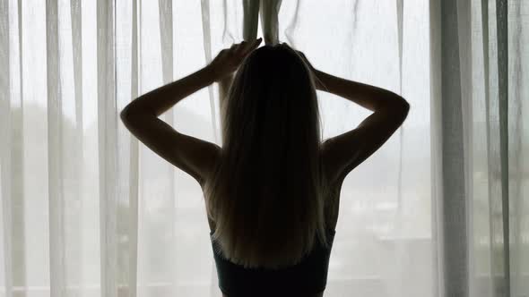 Rear Back View of Woman Opening Curtain Lace Standing at Modern Hotel Looking Through Window