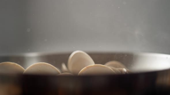 Camera follows adding parsley on cooked clams in a pan. Slow Motion.