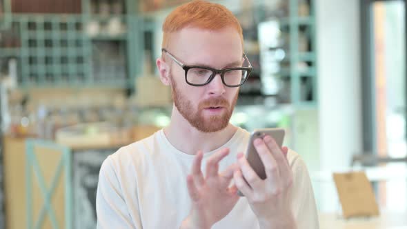 Portrait of Redhead Man Celebrating on Smartphone