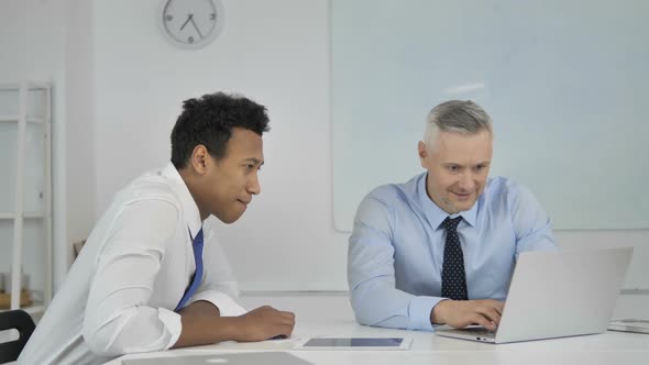 Excited Businessmen Celebrating Success While Working on Laptop