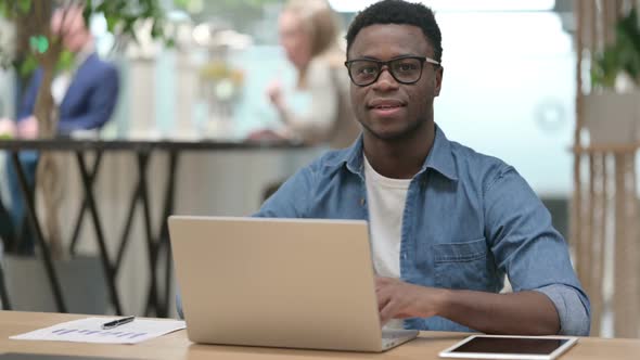 Young African Man Showing Thumbs Up While Working on Laptop