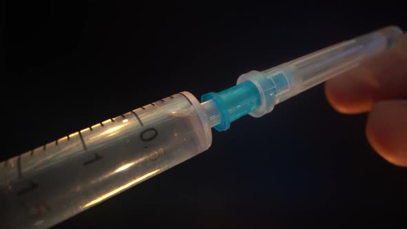 Close-up of a New Disposable Syringe with a Closed Cap on a Needle. The Doctor Removes the Cap From