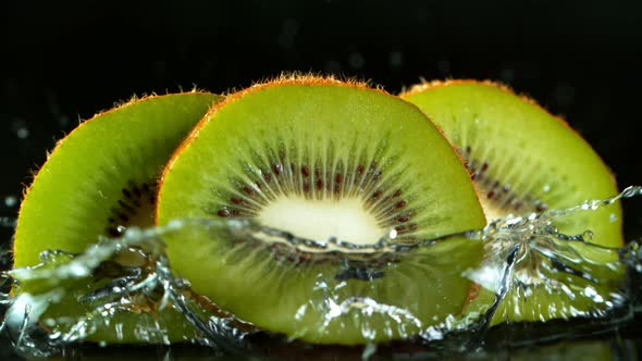 Super Slow Motion Shot of Falling And Splashing Kiwi Slice Isolated on Black Background at 1000Fps.