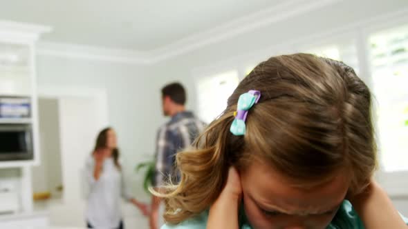 Girl covering his ears while parent quarreling in background