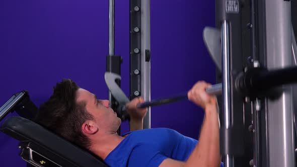 A Young Fit Man Does Inclined Bench Press in a Gym - Closeup From the Side