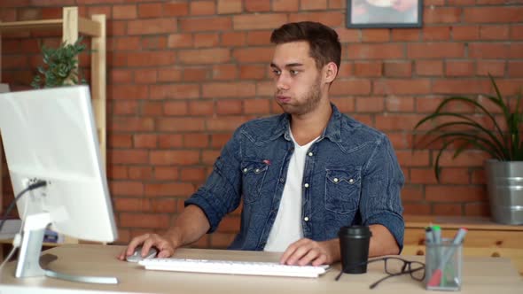 Front View of Stressed Young Man Freelancer Nervously Presses Keyboard and Mouse Trying to Start