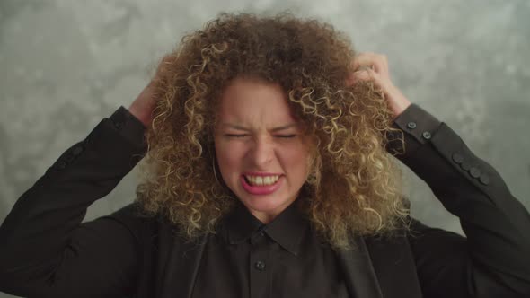 Irritated Pretty Female with Curly Hair Looking with Furious Expression Indoor