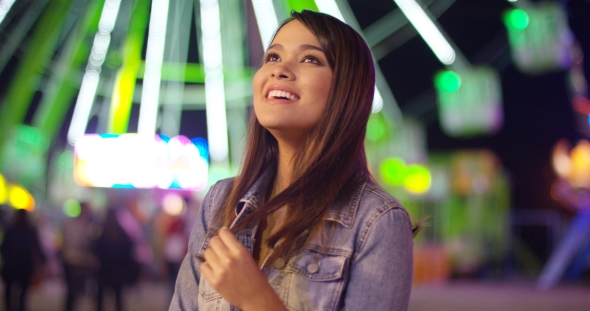 Young Woman at Carnival Stands Looking Up in Awe