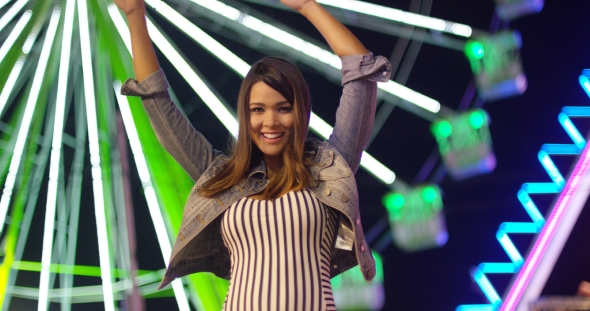 Young Woman at Carnival Stands Looking Up in Awe