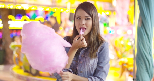 Young Woman Enjoying a Bite of Candy Floss