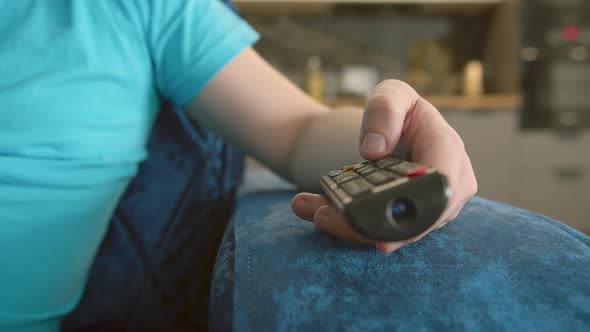 Armrest of the Chair on Which the Hand of a Man with a Remote Control Presses the Buttons