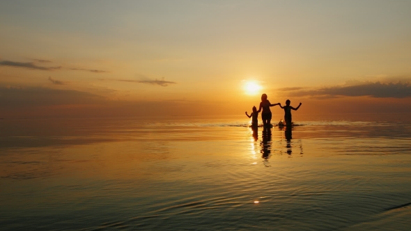 Mother with Two Children Laughing in the Sea at Sunset, Out of the Water