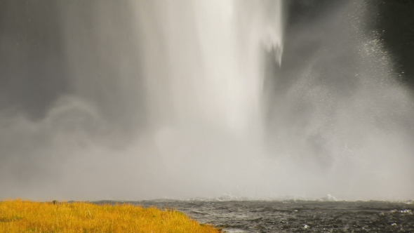 Powerful Stream of Waterfall Is Falling on Ground and Creating River, Yellowed Grass Is in Plan