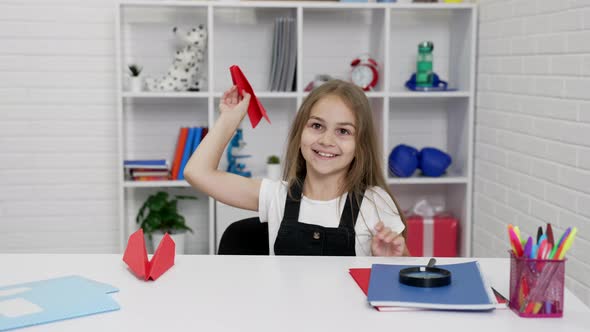 Happy Schoolgirl Having Fun Playing with Paper Plane at School Lesson in Classroom Schooler