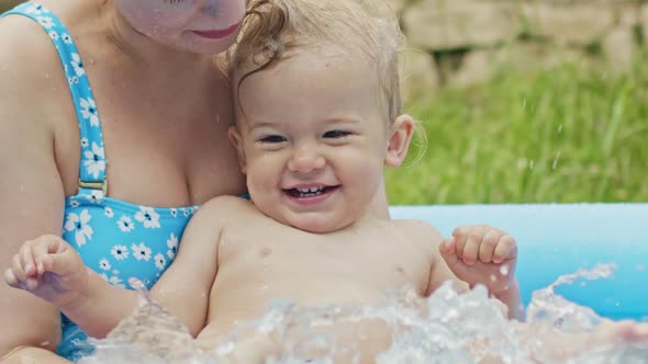 Mother Swimming with Little Baby Boy in Blue Outdoor Pool. Mom and Son Smiling, Having Fun. Concept