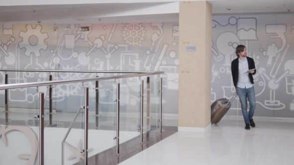 Young Handsome Man Passenger in His 20s Walking in Arrivals Duty Free Zone of Airport Terminal alt