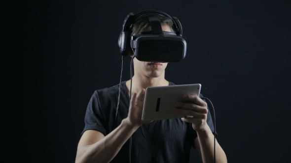 Man Using Virtual Reality Glasses and Holding Digital Tablet Computer