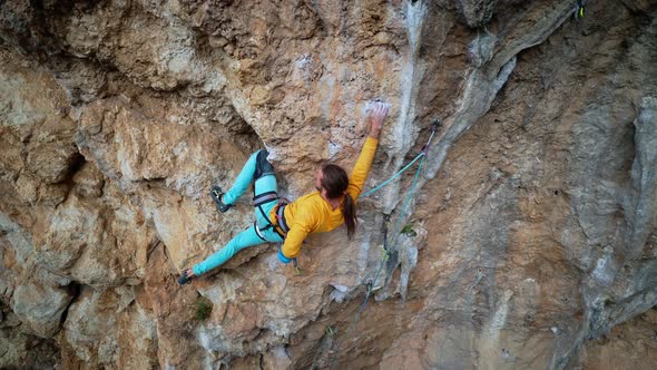 Skilful Athletic Male Rock Climber Resting While Climbs on Overhanging Rock Cliff