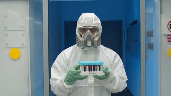 Doctor in Protective Overall and Mask Carrying Tray with Blood Samples for Covid-19 Test