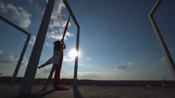 Beautiful Dancer on Aerial Silk. Young Sexy Woman Performs Acrobatic Stunts on the Rooftop Against