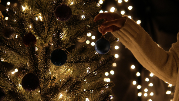 Hangs Christmas Ball On Tree