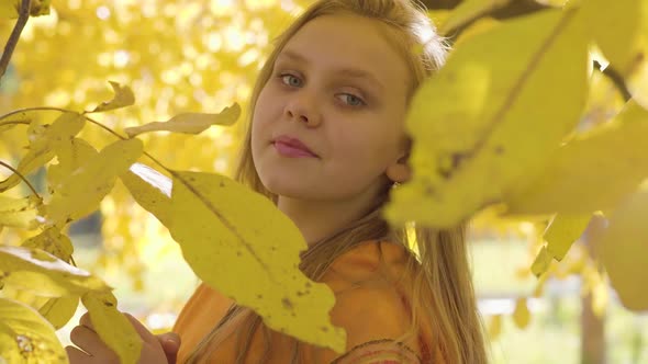 Close-up of a Cute Blonde Caucasian Girl in Mustard Scarf Posing To the Camera, Child with Long Hair