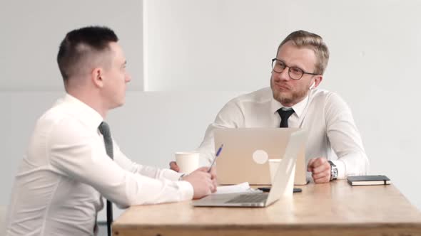 Team of Two Male Office Clerk Working Together, Smiling, Discussing Statistics Drom Laptop.