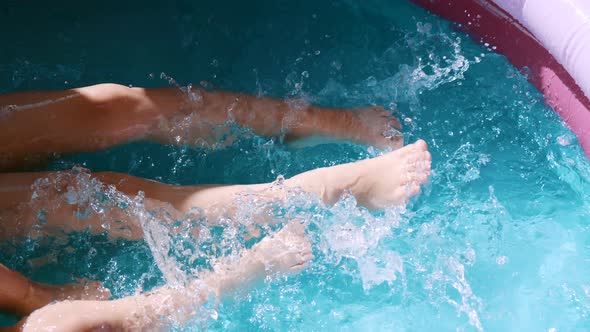 Children spraying water with their feet in an inflatable pool.