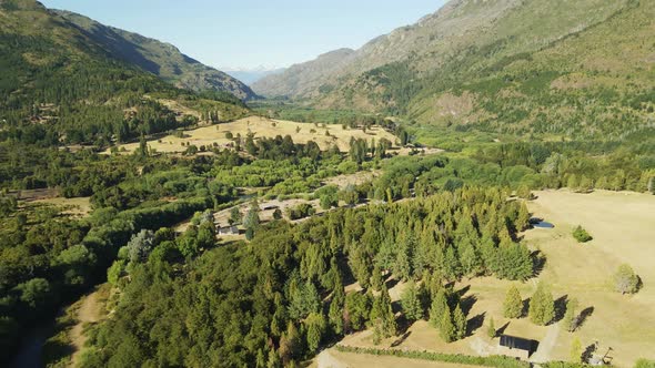 Dolly in lowering over a pine tree forest with El Hoyo valley and Andean mountains in background, Ch