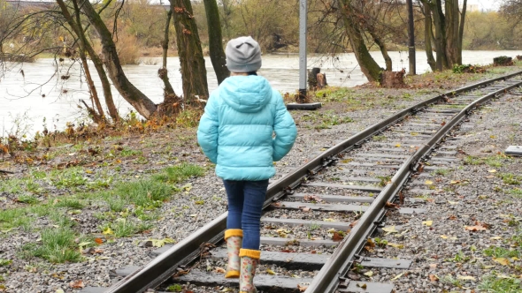 Girl Walking on Railroad Tracks. Rear View of a Girl on the Rails.