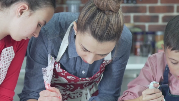 Woman Decorates Christmas Gingerbread Cookies Using a Pastry Bag