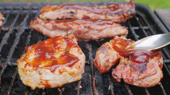 Pieces of Meat on the Grill Smearing Sauce on Top