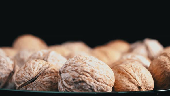 Lot of Walnuts in the Shell are Spinning on a Black Background