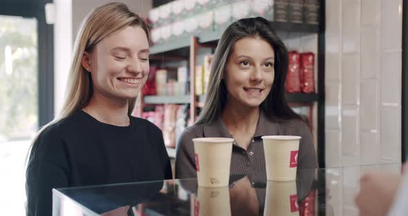 Bartender Serves Two Beautiful Girls with Coffee in the Cafe Payment By Card
