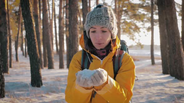 Beautiful Woman Blowing in the Snow in Pine Winter Forest