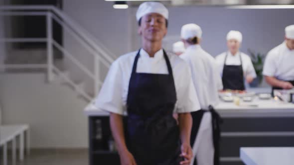 African American female cook working in a restaurant kitchen looking at camera and smiling