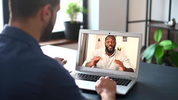 A Focused Man Wearing Casual Shirt Using a Laptop for Video Call