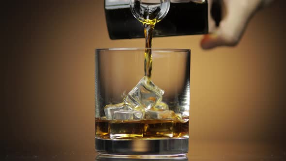 Pouring Whiskey, Cognac Into Glass. Dark Background. Pour of Alcohol Drink