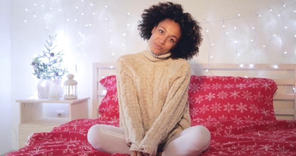 Smiling Confident Young Woman Sitting on Her Bed