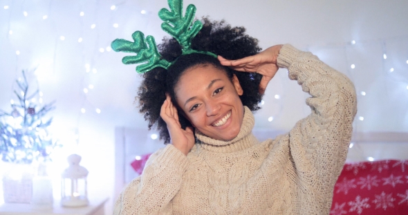 Playful Young Woman Wearing Green Reindeer Antlers