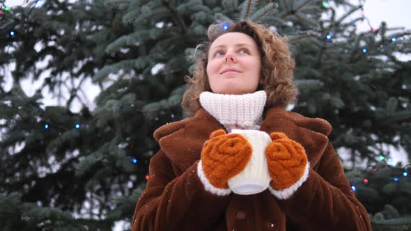 Young Woman In Knitted Gloves Holding Cup Of Coffee Outdoors Enjoying Winter