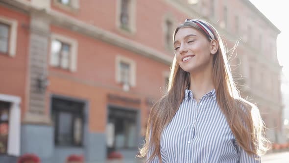 Cute Woman Wearing in Blue and White Striped Dress Shirt Walking on the Street Look at Camera