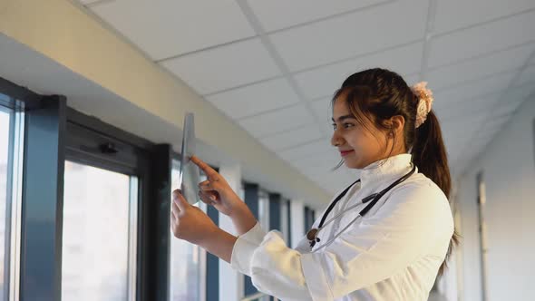 Female Indian Doctor Examines Xray of Lungs Holding It in Hands Indoors