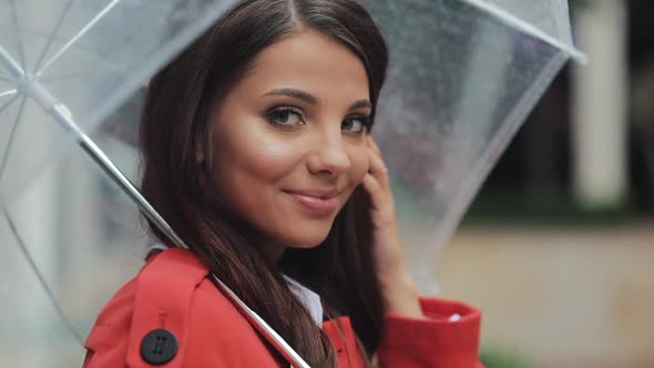 Portrait of Smiling Woman Under Umbrella in City Looking Into the Camera. Spring or Autumn Day