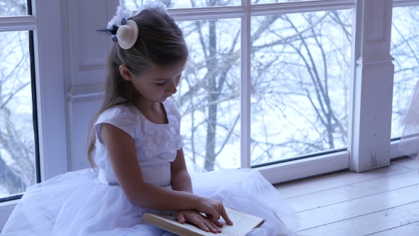 Child Sits On the Floor And Reading a Book Near the Window at Home